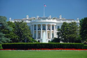 The White House in Washington, D.C., historic presidential residence with a fountain, manicured lawn, and American flag flying above.