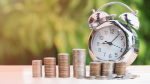 Stacks of coins beside an alarm clock representing VA back pay and retroactive VA disability compensation owed from an earlier effective date.