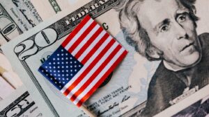 American flag resting on U.S. dollar bills, representing the 2027 COLA increase and its impact on VA disability compensation rates for Veterans.